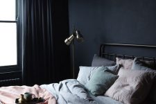 a dark minimalist bedroom with a metal bed, a floor and a pendant lamp, pastel bedding and dak curtains