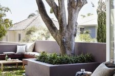 a deck with a built-in wooden bench, with some greenery and a tree and a soft lounger is a welcoming space to be