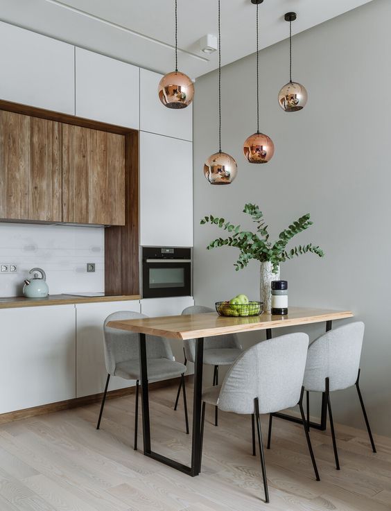 a minimalist kitchen with white and wood cabinetry, pendant lamps, a wooden table and grey chairs is very chic