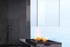 a minimalist metal, stone and glass fireplace that makes a statement and brings coziness to the space