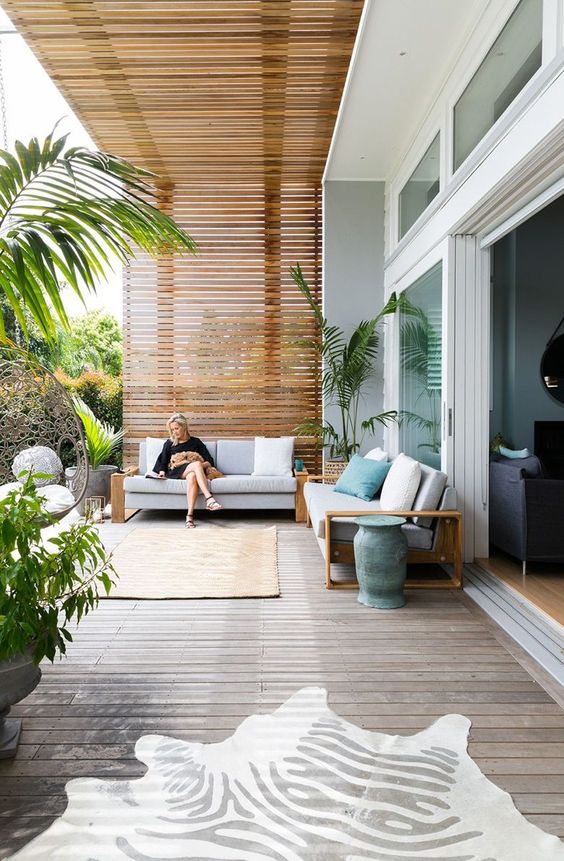 a modern deck with a couple of comfortable sofas, touches of aqua blue and potted greenery