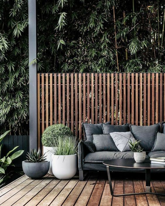 a modern deck with black furniture, grey upholstery, modern pots with greenery is very chic with its restraint color palette