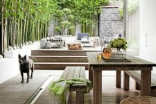 a modern deck with neutral furniture, printed textiles, greenery covering the whole wall and a wooden table