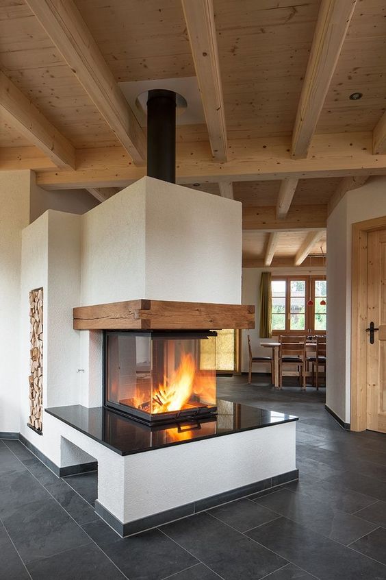 a modern three side fireplace with a glass cover, a black countertop and wooden beams is a stylish piece