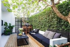 a monochromatic deck with a living wall, a bar space, a large black sofa and a black table plus candles
