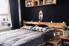 a moody industrial bedroom with black walls, pallet furniture and boho decor and plants is very bold and chic