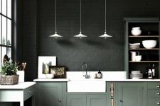 a moody kitchen with dark green brick walls, green cabinetry, white countertops and white pendant lamps is a statement