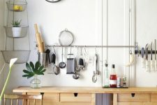 a neutral kitchen cooking space of two IKEA Forhoja carts and long railing for hanging things