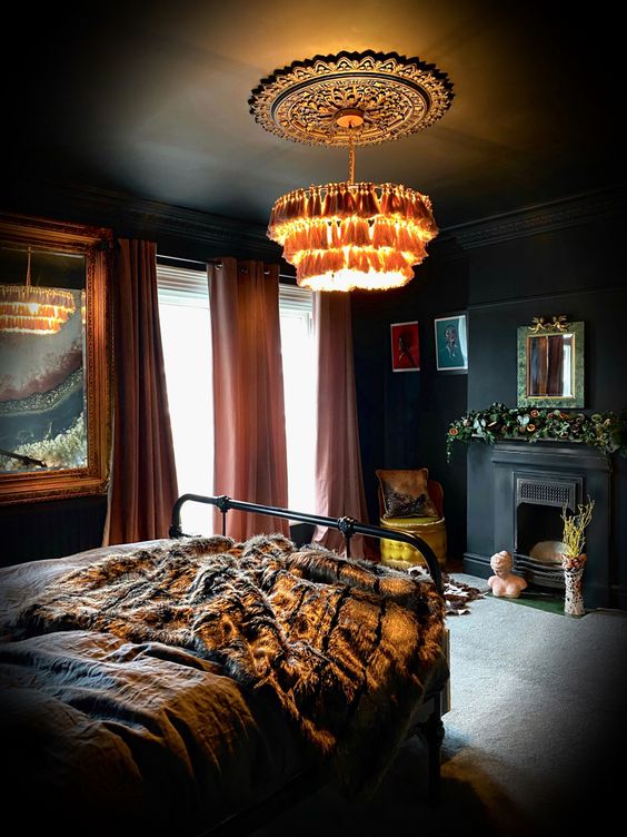 a refined moody bedroom with black walls and a ceiling, with a tassel chandelier, a fireplace and a metal bed plus artworks