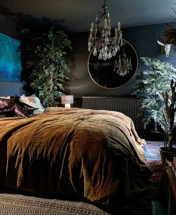 a refined vintage moody bedroom with dark walls, a black radiator, a crystal chandelier, potted plants and dark bedding