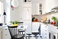 a small bold kitchen with white cabinetry, a skinny tile backsplash, a quirky pendant lamp, a black and white floor and a small dining zone