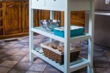 a stylish farmhouse kitchen island of a light blue IKEA Forhoja cart with a wooden countetop