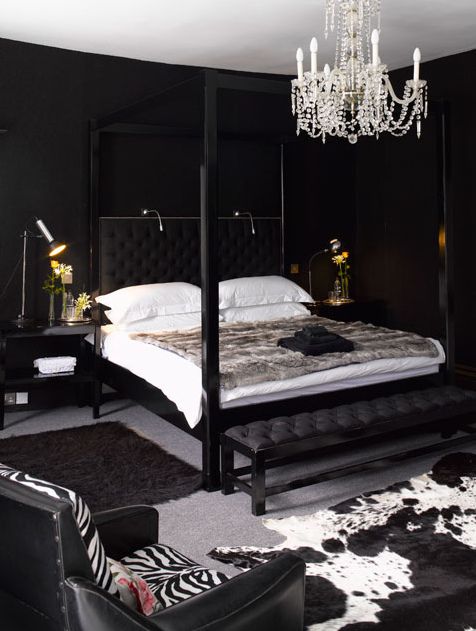 an elegant and glam moody bedroom with black furniture, a crystal chandelier and lights and lamps everywhere