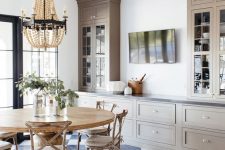 an elegant farmhouse kitchen with taupe cabinets, a rustic dining space with a round table and chairs of wood is very cozy
