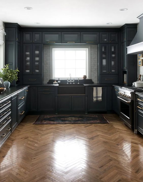 an elegant moody kitchen with black cabinetry, a white tile backsplash, a wooden wall and a boho rug is all chic