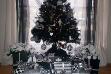 03 a black Christmas tree with lights, black and white ornaments, ornaments shaped as hearts and stars, feathers and piles of Christmas gifts