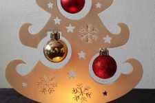 05 a creative plywood tabletop Christmas tree with cutout stars and snowflakes, red and gold ornaments and a little tealight