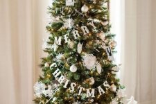 06 a cute Christmas tree decorated with lights, white and gold ornaments, letter banners and a large white bow on top