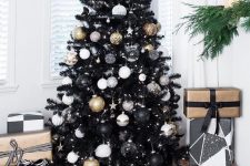 08 a black Christmas tree with white, sheer, gold and black ornaments and lights and piles of black and gold gifts under the tree