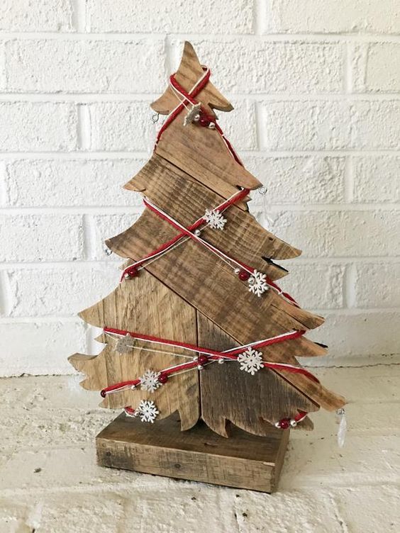 a wooden tabletop Christmas tree decorated with yarn, beads and mini snowflakes is a lovely decoration with a rustic feel
