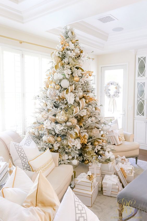 a glam gold and white Christmas tree with ribbons, metallic ornaments, twigs and leaves plus piles of gifts