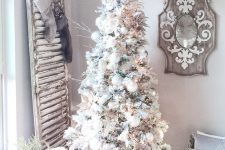 11 a flocked Christmas tree with white and silver ornaments, frosted twigs, pinecones and paper garlands and ornaments