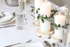 13 a beautiful white Christmas tablescape with wood slices, white porcelain, silver cutlery, elegant glasses, candles and some greenery