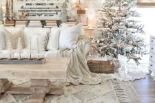 16 a lovely all-neutral Christmas living room with a flocked Christmas tree, white paper snowflakes, white pillows and blankets and some greenery