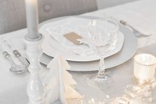 17 a minimalist white Christmas tablescape with lights, mini stars and beads, candles, white porcelain and white cutlery is chic