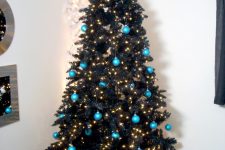 18 a black Christmas tree decorated with lights and turquoise ornaments for a contrast plus an oversized silver glitter star on top
