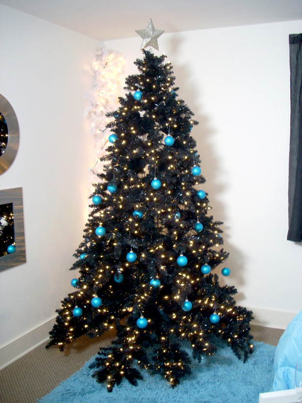 a black Christmas tree decorated with lights and turquoise ornaments for a contrast plus an oversized silver glitter star on top
