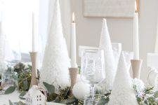 18 a pretty white Christmas tablescape with bottle cleaner tabletop trees, pompoms, a greenery runner, white house ornaments and wooden chargers