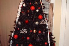 20 a black Christmas tree with lights, gold, navy, red and silver ornaments, white patterned ribbons and a large bow on top