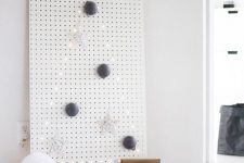 22 a white pegboard with a Christmas tree lined out with lights and with some ornaments is an ultra-minimalist idea