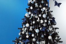 23 a black Christmas tree with silver and navy ornaments, bows and birds, butterflies and other pretty decor is very elegant