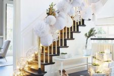 24 white 3D paper ornaments covering the railing, lights, greenery and a large white faux fur rug and stacks of gifts for a winter wonderland feel
