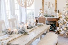 25 white Christmas decor with faux fur on benches, a white knit runner, candles, flocked fir branches and a white beaded chandelier