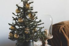a Christmas tree with lights and gold ornaments is a cool idea for any table styling during the holidays
