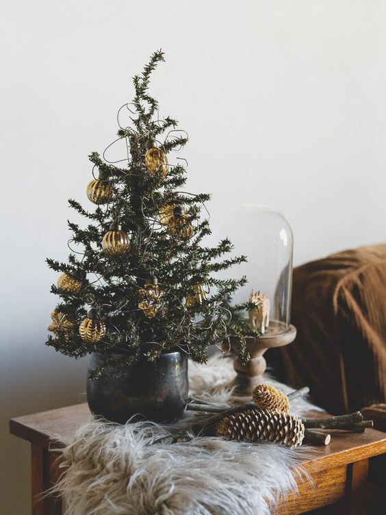 a Christmas tree with lights and gold ornaments is a cool idea for any table styling during the holidays