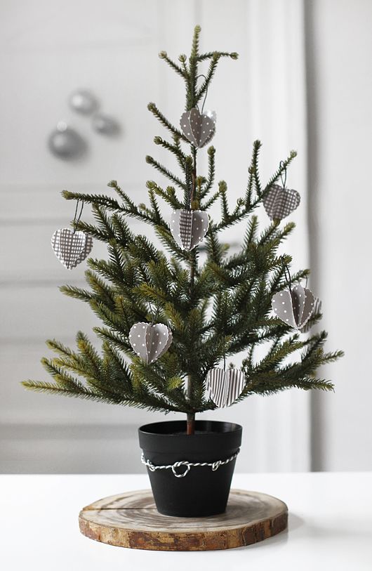 a Scandinavian tabletop Christmas tree in a black pot with grey and white paper ornaments is a stylish idea