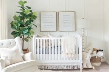 a beautiful neutral nursery with a paneled wall, white furniture, layered rugs, a Moroccan ottoman and a woven pendant lamp