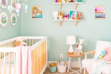 a beautiful nursery with turquoise walls, pink and white bedding, shelves with colorful books and toys and some linens
