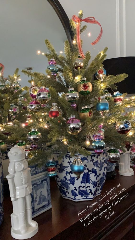 a beautiful tabletop Christmas tree with colorful vintage ornaments in a blue pot is a lovely decor idea