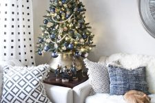 a beautiful vintage-inspired Christmas tree decorated with lights, navy ornaments, beaded garlands, snowflakes and put into a lovely pot