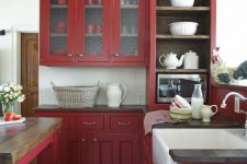 a berry red vintage kitchen with white tiles, black countertops and a vintage table as a table and kitchen island