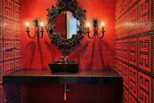 a bold and refined black and red bathroom with a built-in vanity, black appliances, a crystal chandelier and a refined mirror