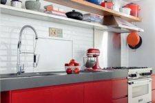 a bold kitchen with sleek red cabinets, a thick concrete countertop, a white tile backsplash and open shelves instead of upper cabinets