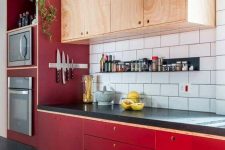 a bold mid-century modern kitchen with bright red lower cabinets and neutral upper ones plus a white tile backsplash