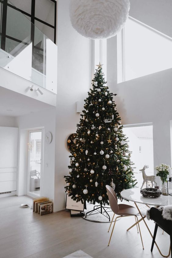 a bold modern Christmas tree decorated with lights, white, metallic ornaments of various shapes and with a star topper