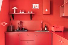 a bold red solid kitchen with chic cabinets, shelves, backsplashes and countertops is completely red and statement-like